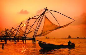 A sunset over fishing nets and boat in Cochin (Kochi), India