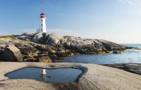 Peggys Cove Lighthouse with rocks and glistening water in Nova Scotia, Canada