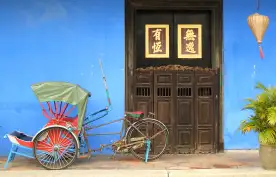Tricycle parked in front of large brown door in Penang, Malaysia
