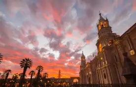 Stunning colorful sky and clouds at dusk in Arequipa, famous travel destination and landmark in Peru. Wide angle view from below of the colonial Cathedral. Panoramic frame.