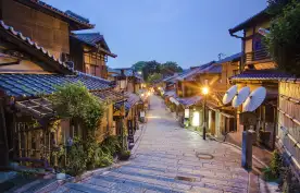 Old street of Kyoto in a Japanese town, lit by street lights under an early evening sky