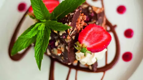 Close-up of chocolate dessert with chocolate sauce decoration, strawberries and mint
