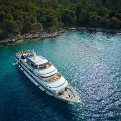 Square image of yacht ship anchored in crystal blue waters of a secluded bay