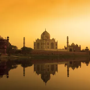 Taj Mahal at sunset reflected in the calm Yamuna river in India