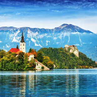 Church on the Island and ancient castle on top of a rock with European Alps in background at Lake Bled, Slovenia