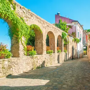 Old stone wall with arches and flowers on old European street, Ravello, Amalfi coast, Italy