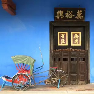 Tricycle parked in front of large brown door in Penang, Malaysia