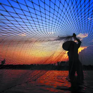 Fisherman casting a net before sunrise along the Mekong River, Thailand.