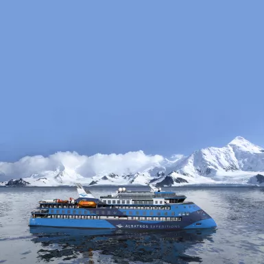 Exterior of the Ocean Albatros ship with snowy mountains in background