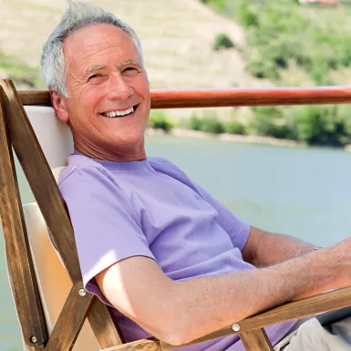 Smiling man relaxing in a chair while reading, on a boat deck