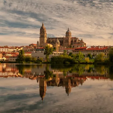 Salamanca Cathedral reflected on Tormes River during sunset in Salamanca, Spain