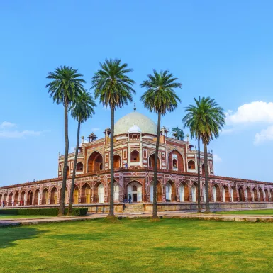 Front view of Humayun's Tomb with tall palm trees in Delhi, India