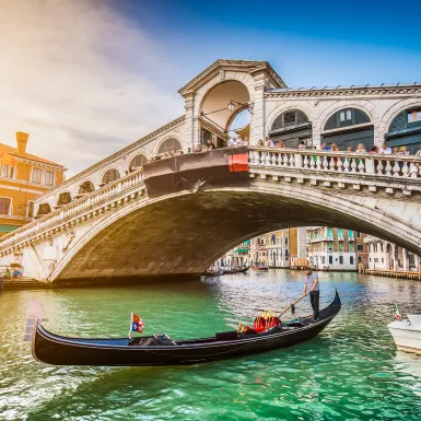 Gondola on Canal Grande with Rialto Bridge at sunset in Venice, Italy