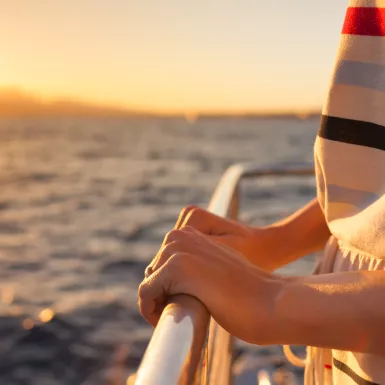 Close-up of hands holding onto rail on a yacht during sunset