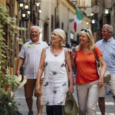 Mature couples looking around old town Italy as evening draws in.  Little lights can be seen outside of the buildings.