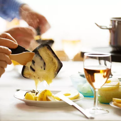 Close-up of family serving Raclette, a traditional Swiss Winter meal