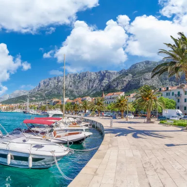 Makarska harbor under a blue cloudy sky, surrounded by the Croatia mountain range