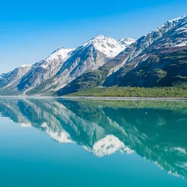 Snowy mountains being reflected on clear waters in Glacier Bay National Park, Alaska