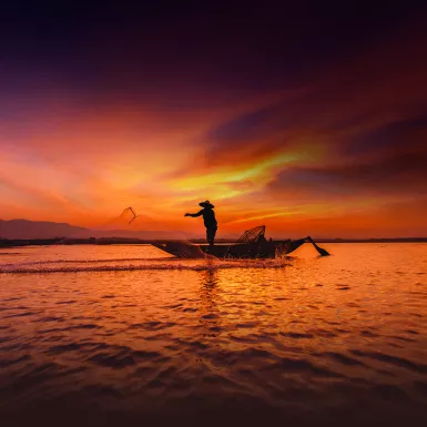 Silhouette of traditional fisherman throwing net fishing inle lake at sunrise time, Myanmar