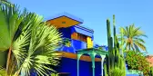 Vibrant yellow and blue house, with palm trees in front of it in Marrakech