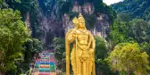 Entrance steps to Batu cave, Hinduism temple in Kuala Lumpur with colourful stairs and a large golden statue 