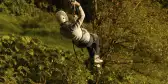 Person zip-lining in forest area