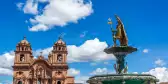 A golden fountain and an impressive religious building in Cuzco Main Square, Peru