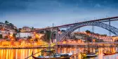 Rabelo boats on the Douro River and Porto skyline illuminated at night in Portugal