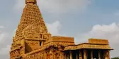 Hindu Temple showcasing Chola architectural style, built with a pyramid shaped spire. Stone steps lead to the entrance hidden under a column-supported roof