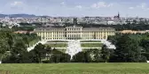 Elevated view of Schönbrunn Palace in Vienna, with the city's skyline in the background. 