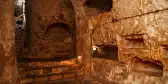 Underground in St Paul’s Catacombs, smooth carved stone walls featuring shelves to lay created for a Christian resting place, Malta