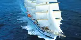 Royal Clipper in transit across the ocean with multiple white sails deployed  