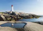 Peggys Cove Lighthouse with rocks and glistening water in Nova Scotia, Canada