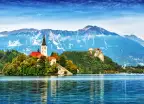 Church on the Island and ancient castle on top of a rock with European Alps in background at Lake Bled, Slovenia