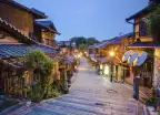 Old street of Kyoto in a Japanese town, lit by street lights under an early evening sky