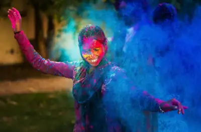 Young woman dancing around a cloud of color powder while celebrating the indian Holi day