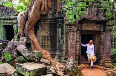 A Woman paused in the doorway of an ancient ruin of Ta Prohm, looking in up in admiration.