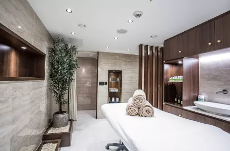 Bright and cleanly Spa room featuring a massage table topped with fresh folded towels, BW Oscar Wilde