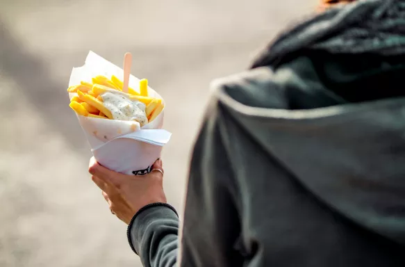 Tourust holding cone of French fries in the streets on Brussels, Belgium