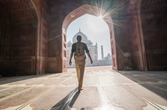 Young man walking towards the Taj Mahal at sunrise in Agra, India