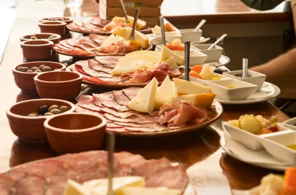 Portuguese cheese, ham and salami boards being prepared by restaurant employees at the counter table. 