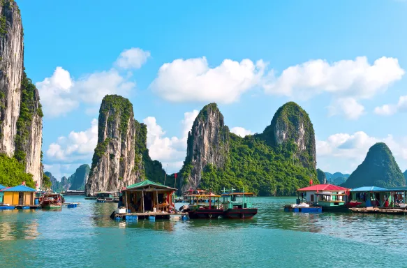 Floating village and rock islandscovered in vegetation in Halong Bay, Vietnam