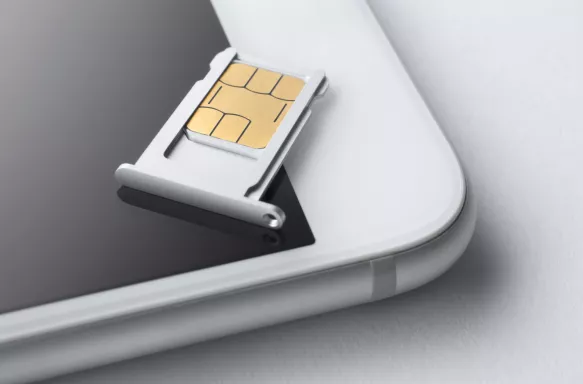 Close-up of a sim card and sim card try on a white mobile phone