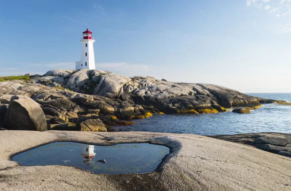 Peggys Cove Lighthouse with rocks and glistening water in Nova Scotia, Canada