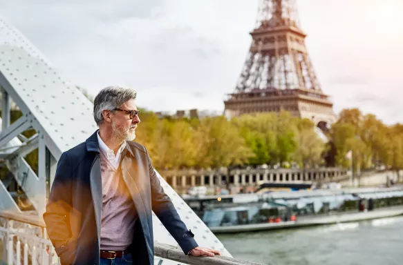 Shot of a handsome mature man leaning on a railing in Paris with the Eiffel Tower in the background.