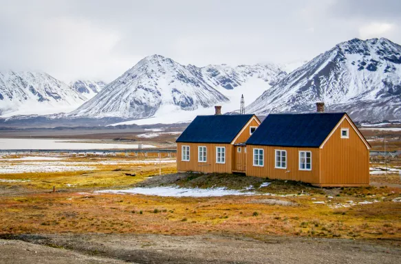 Yellow houses on yellow tundra grass with snowy mountains in Svalbard, Norwegian Arctic