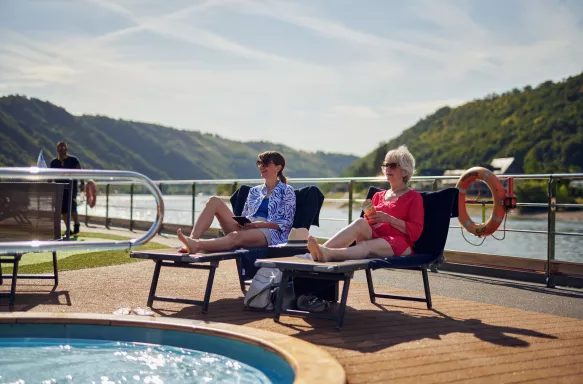 Mature and senior woman sunbathing together by a pool on a cruise ship