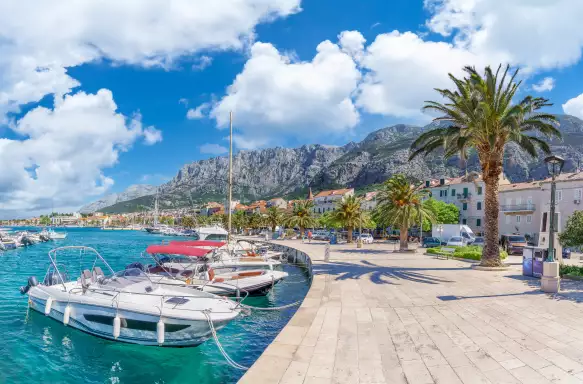 Makarska harbor under a blue cloudy sky, surrounded by the Croatia mountain range