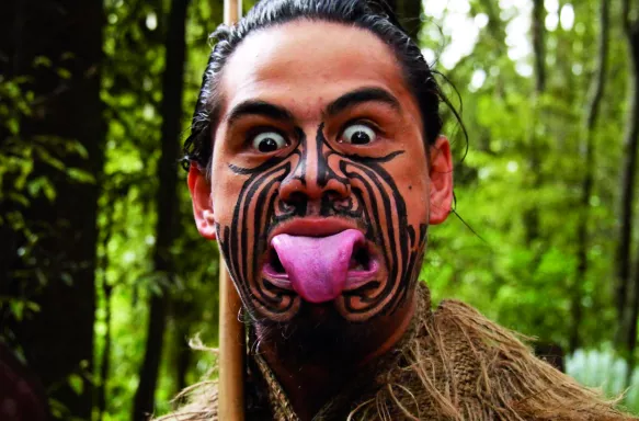 Maori man with his tongue stuck out in a Pūkana, an expression worn for when performing a Haka or song