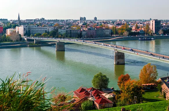 Aerial of Novi Sad's Varadin Bridge spanning across the Danube River, with a background of the cityscape